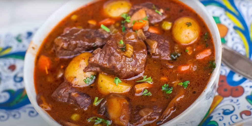 A steaming bowl of spicy beef stew recipe with tender beef, carrots, and potatoes, garnished with fresh parsley.